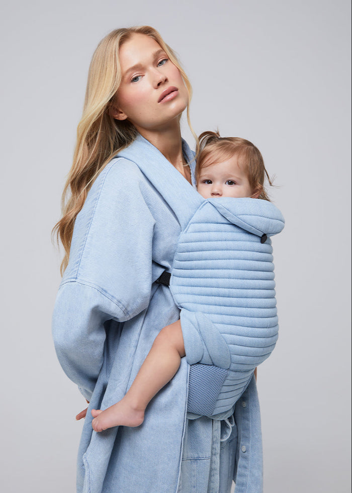 model in all denim with a baby in the light blue denim baby carrier