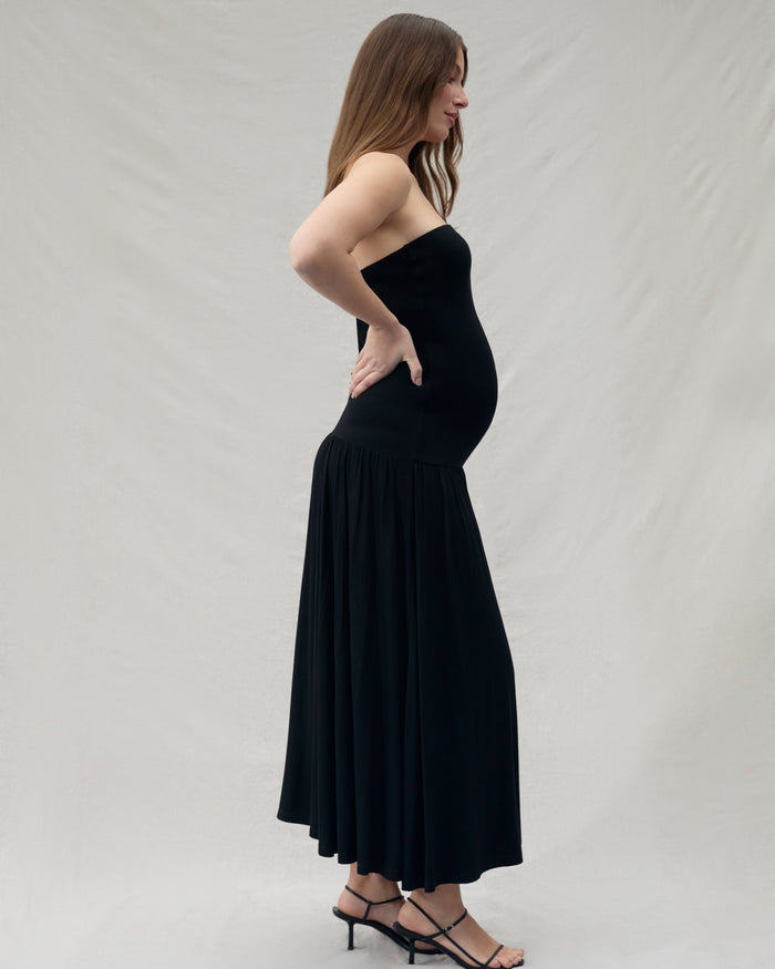 Woman wearing a black strapless dress against a plain background