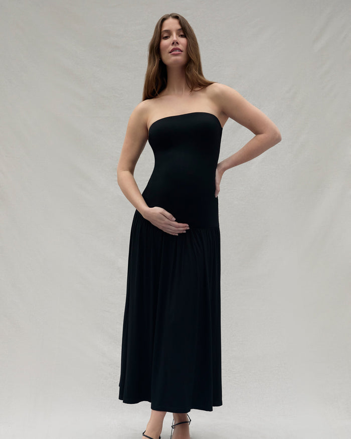 Woman wearing a Bumpsuit black strapless dress against a plain background