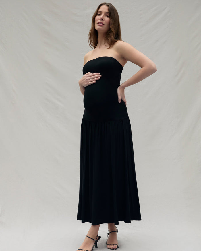 Woman wearing a black strapless dress against a plain background