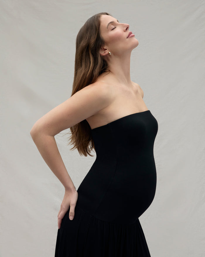 Woman wearing a black strapless dress against a plain background