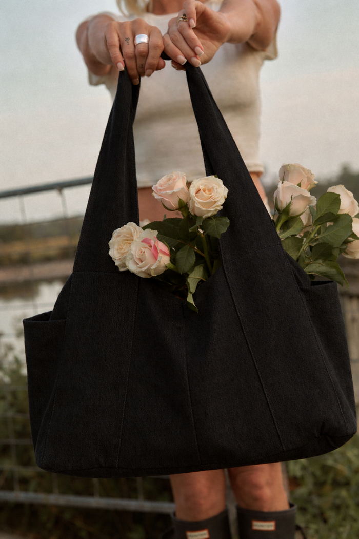 lady holding a black denim diaper bag  with roses inside