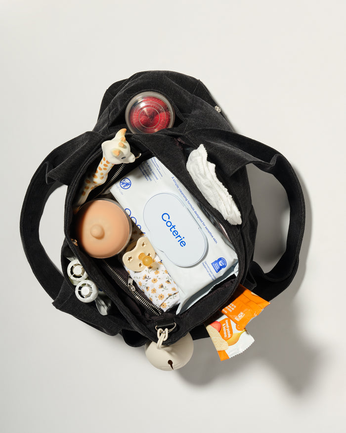 A black diaper bag shown from above, open to reveal baby essentials inside