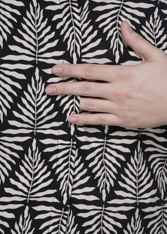 S=Hand touching black fabric with white leaf pattern