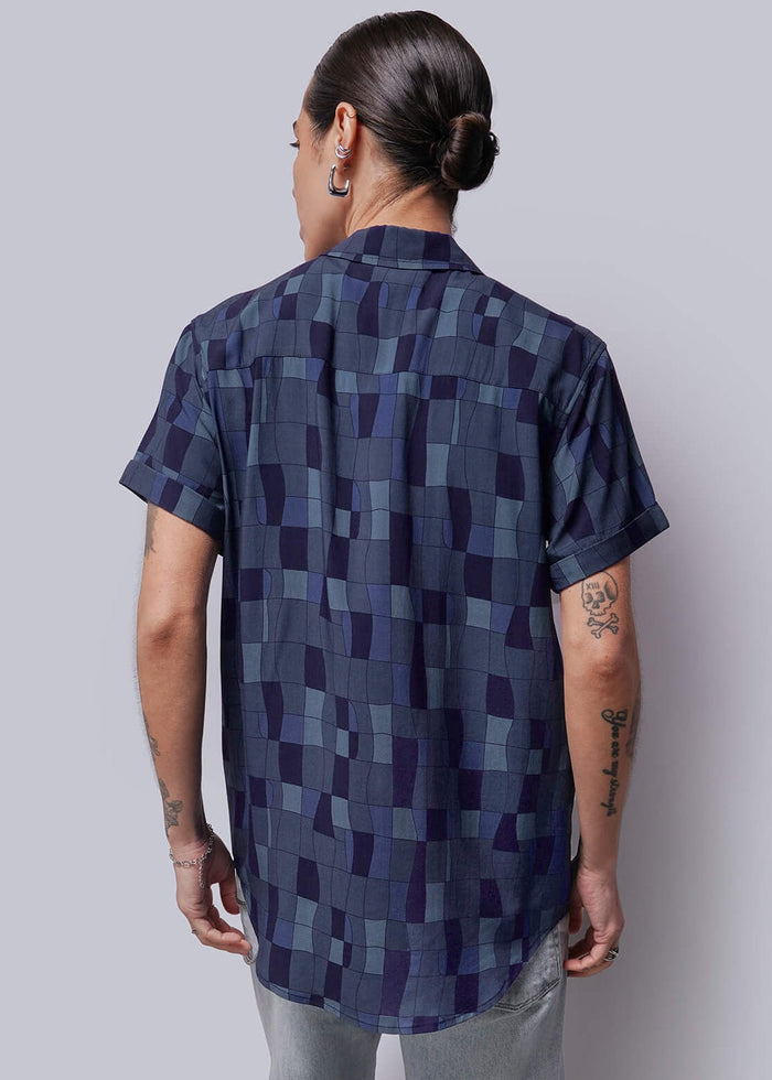S=Person wearing a patterned shirt and shorts standing against a plain background