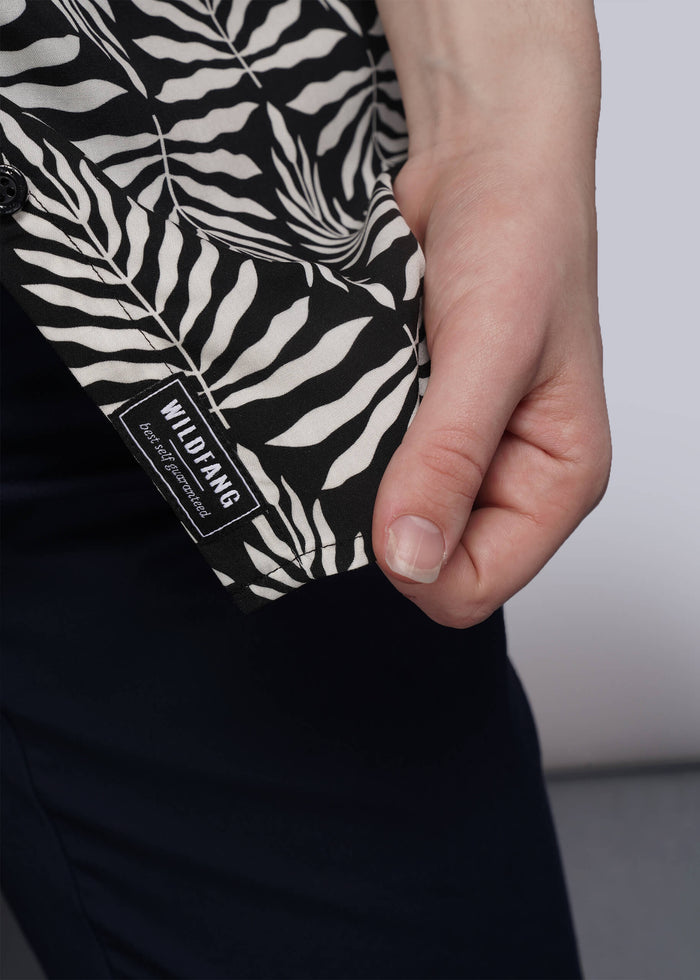 S=Person holding a black and white patterned button up with brand label.
