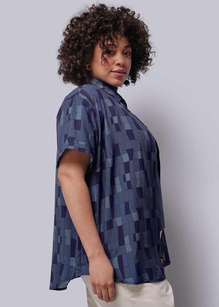 1X=Person wearing a blue patterned shirt against a plain background