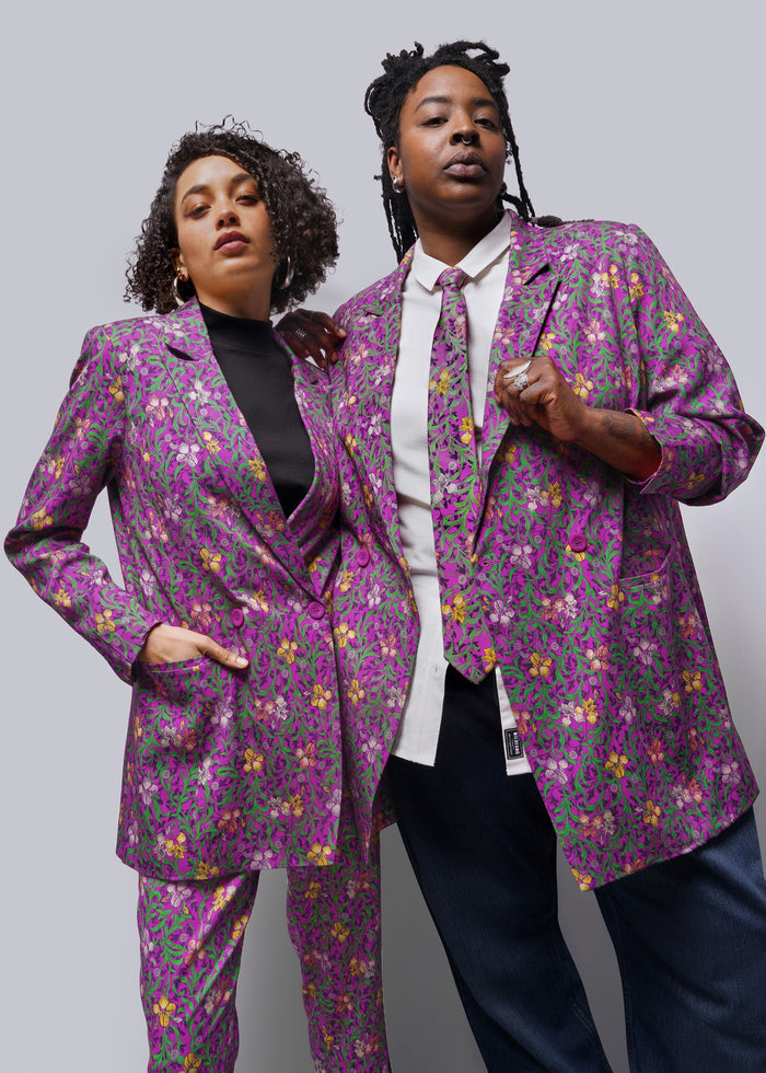 Two people wearing purple printed blazers against grey background