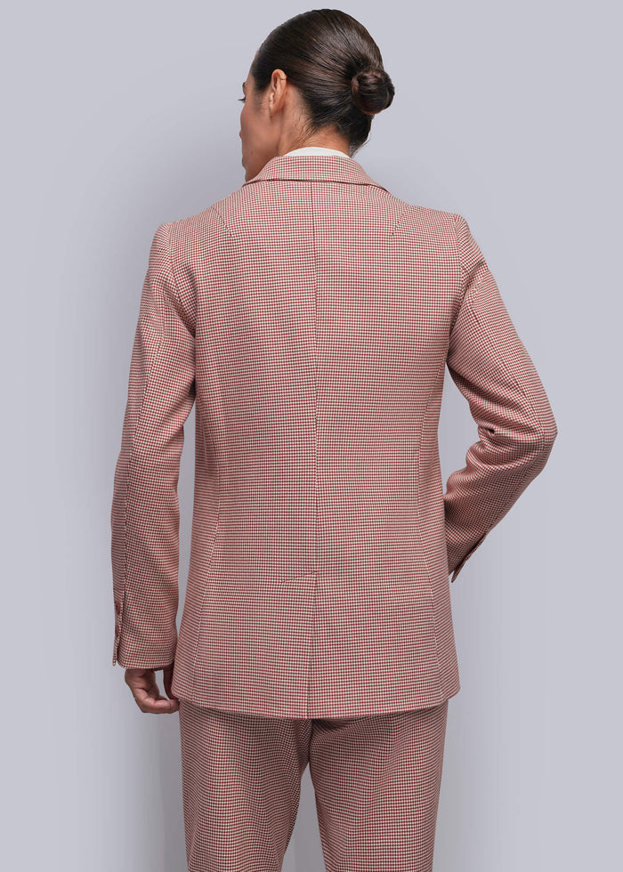 S=A person viewed from the back wearing a matching dusty red and white micro-check patterned suit, consisting of a blazer and trousers, against a solid light gray background.