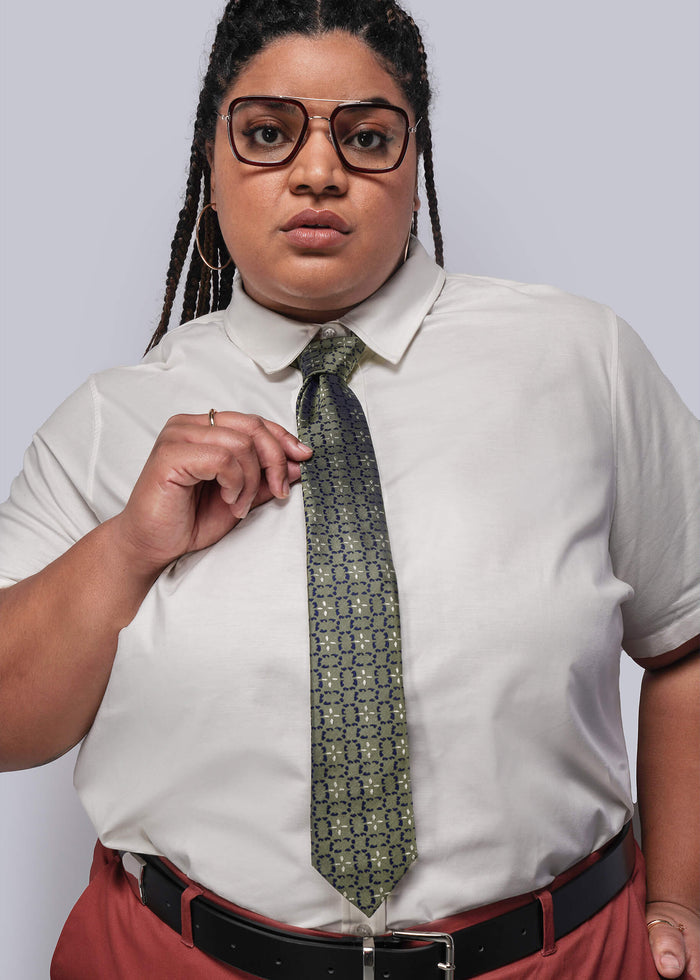 Person wearing a light-colored shirt with a patterned tie against a plain background