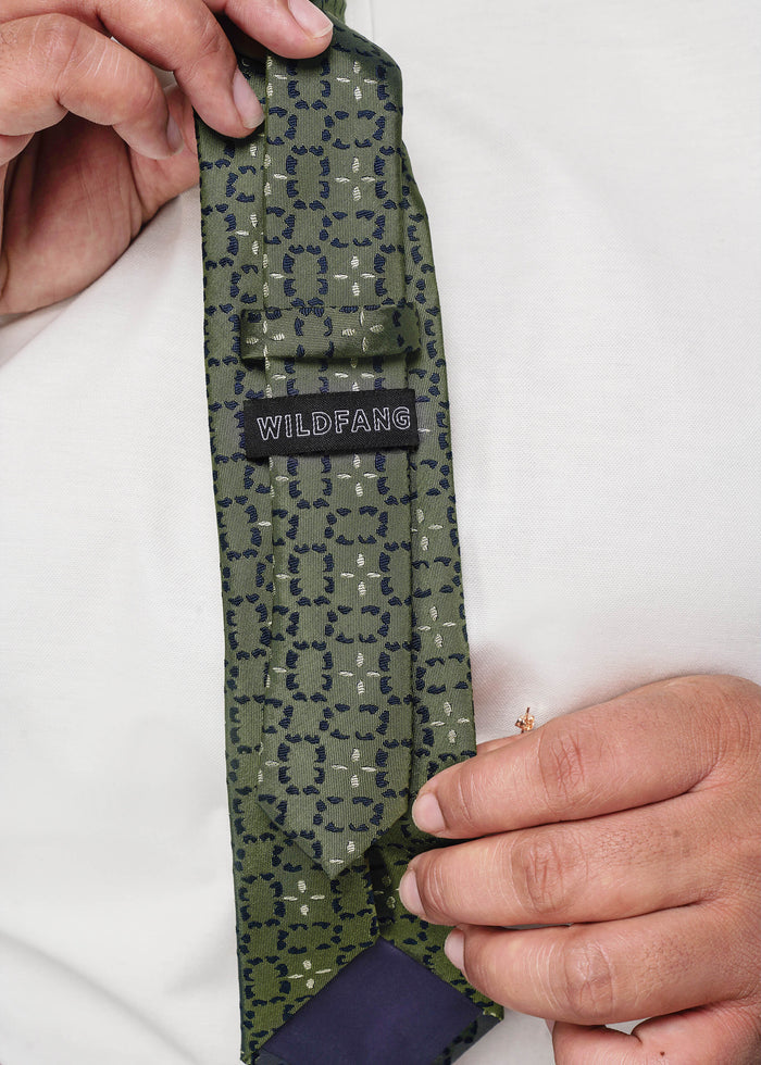 Gray patterned tie with 'WILDFANG' label held by a person against a white background