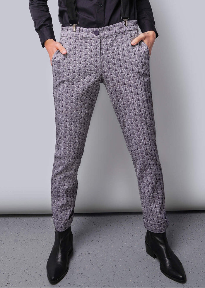 S=Person wearing a dark shirt, suspenders, and patterned pants against a plain background