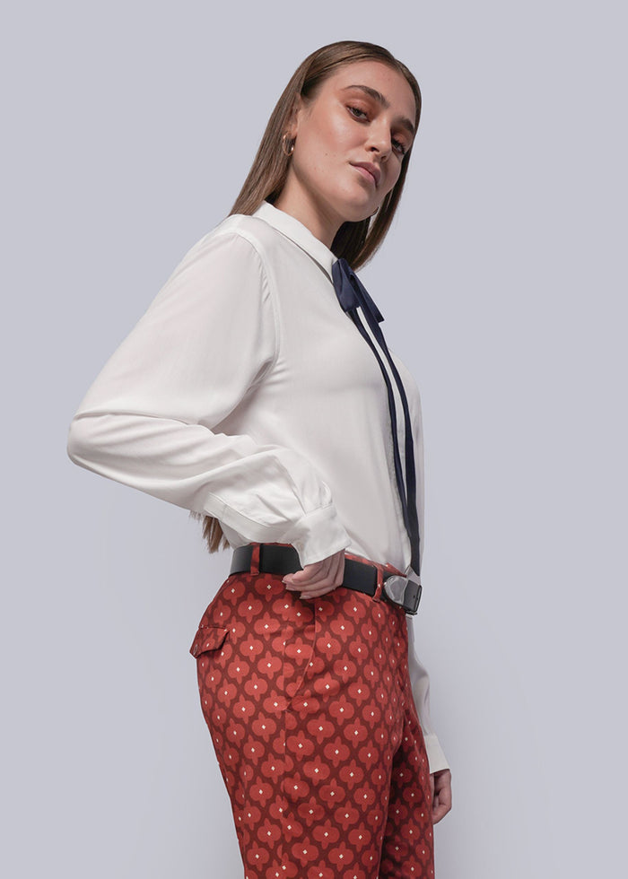 S=Person wearing a white blouse and red patterned pants against a light gray background