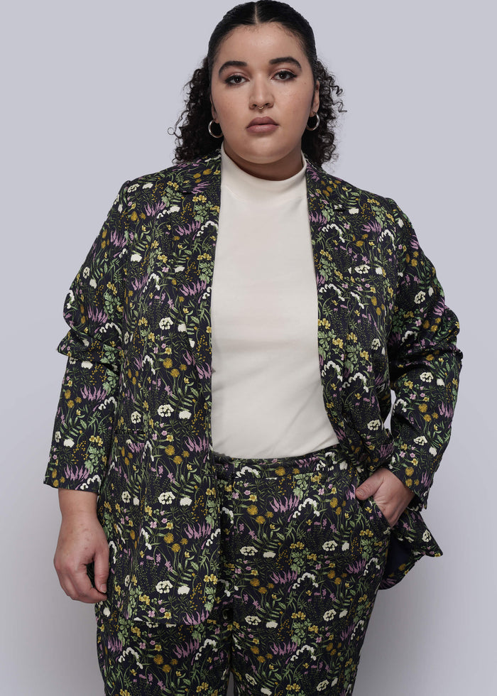 1X=Person wearing a floral patterned suit against a plain background