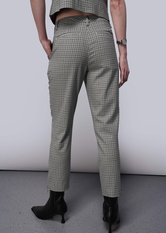 S=Back view of person wearing plaid pants and black boots on a plain background