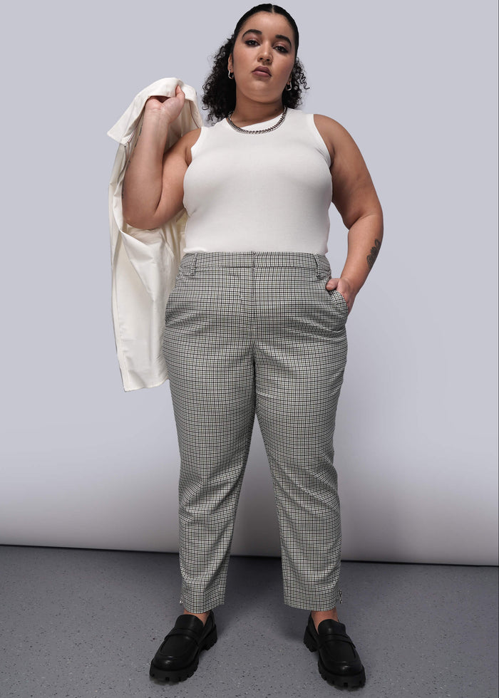 1X=Person wearing a white sleeveless top and plaid pants with loafers against a plain background