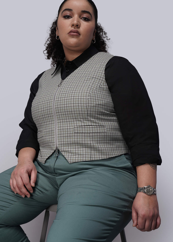 1X=Person wearing a checkered vest over a black shirt with green pants on a plain background