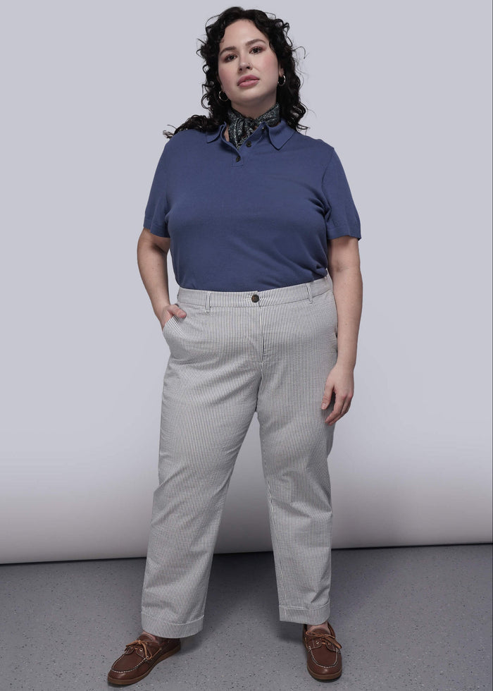 1X=Person wearing a blue shirt and light blue striped pants against a plain background