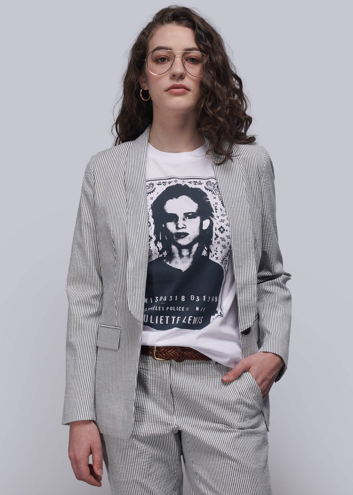 S=Person wearing a light blue striped seersucker blazer over a graphic t-shirt with a plain background