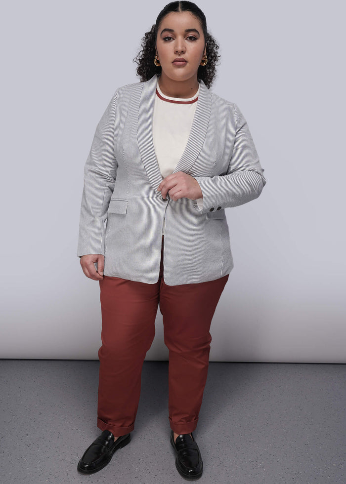 1X=Person wearing a light blue striped seersucker blazer, white shirt, red pants, and black shoes on a plain background