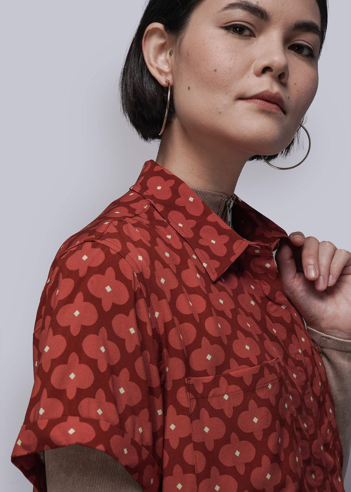 S=Woman wearing a red patterned shirt against a plain background