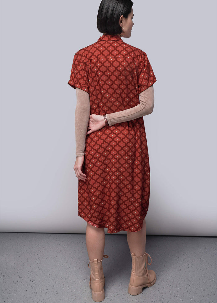 S=Woman wearing a red patterned dress with beige boots on a plain background