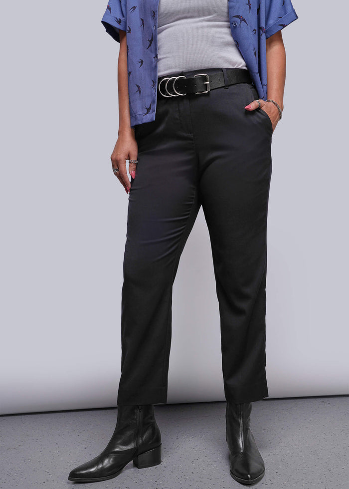 S=Person wearing black pants with a blue shirt and white top against a plain background
