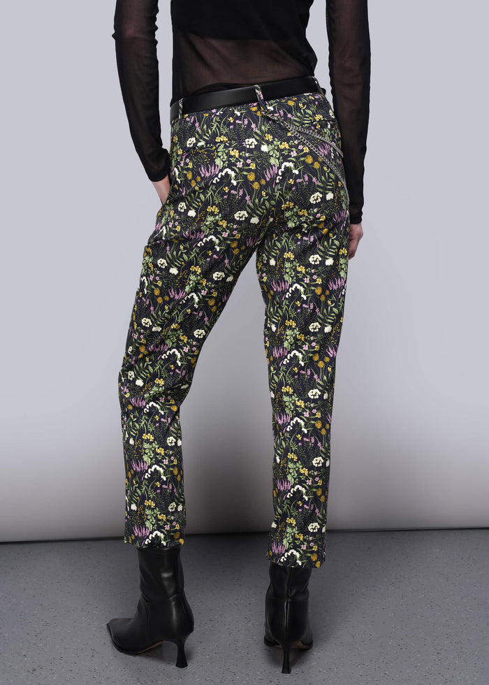 S=Person wearing floral patterned pants on a plain background