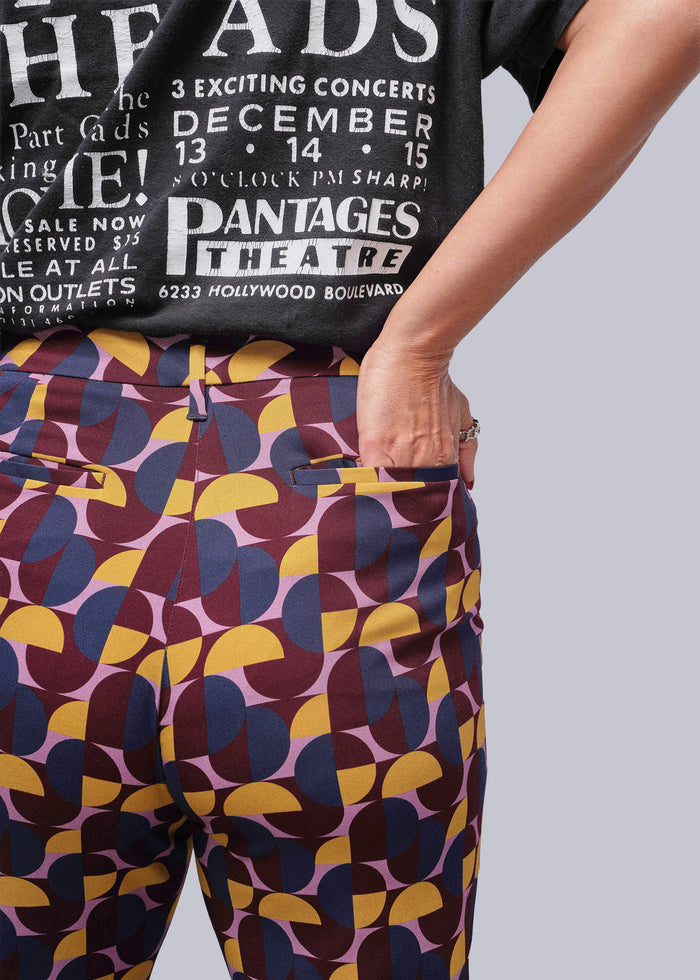 S=Person wearing a black t-shirt with white text and colorful patterned pants.