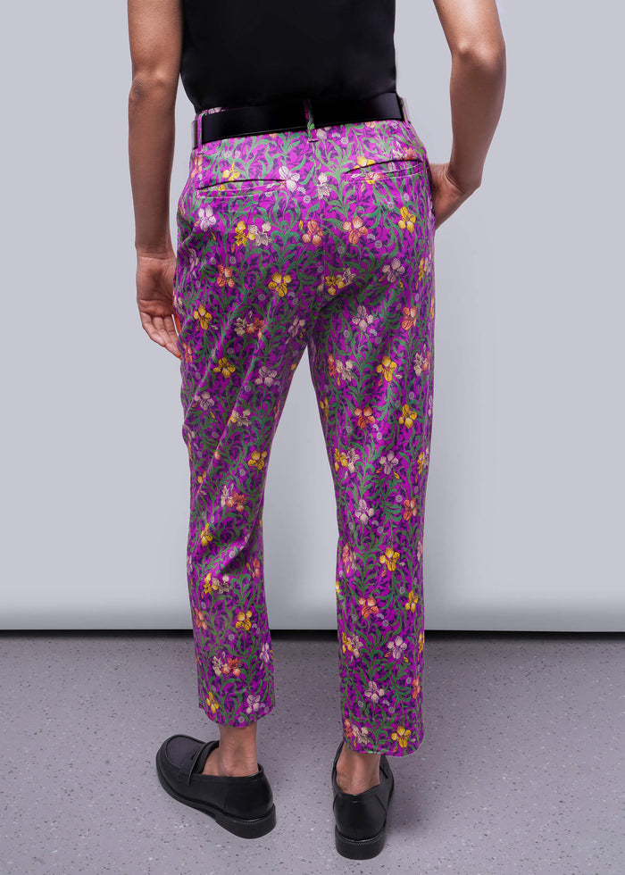S=Person wearing purple floral pants against a plain background
