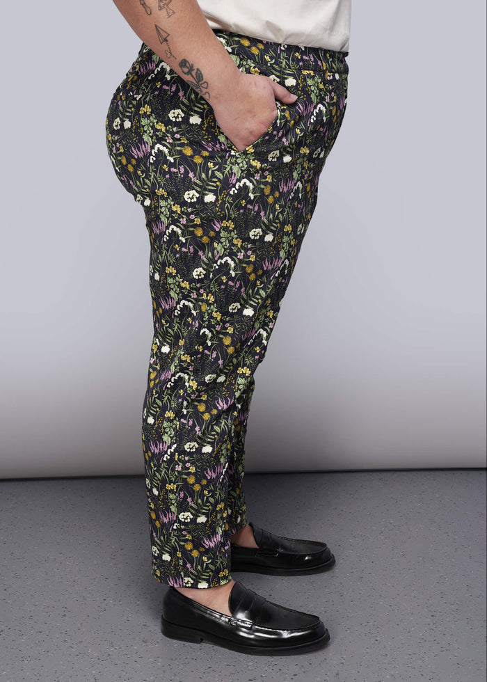 1X=Person wearing floral-patterned pants and black shoes on a plain background