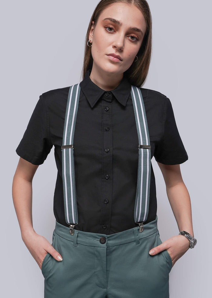 Person wearing a black shirt with teal and white stripe suspenders and teal pants on a plain background