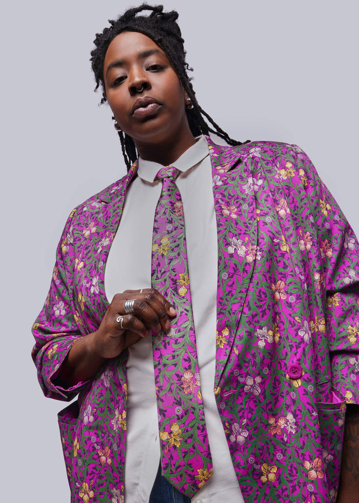 Person wearing a colorful floral-patterned shirt over a white shirt on a plain background
