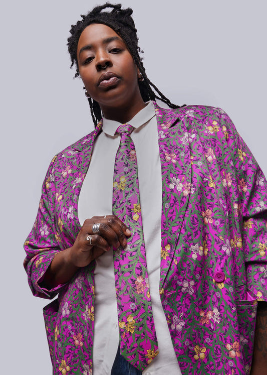 Person wearing a colorful floral-patterned shirt over a white shirt on a plain background