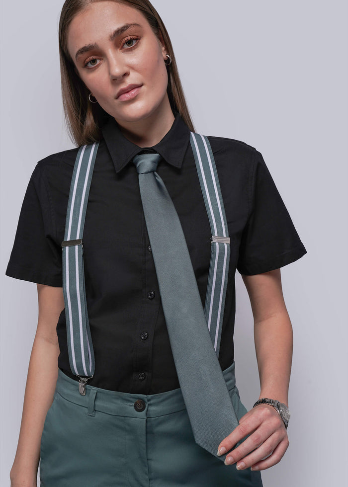 Person wearing a black shirt, blue tie, and suspenders on a plain background