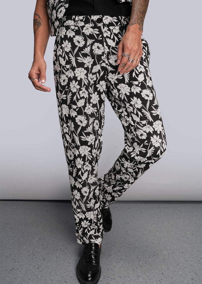 S=Pictured from waist down, person wearing black and white floral pants against a plain background