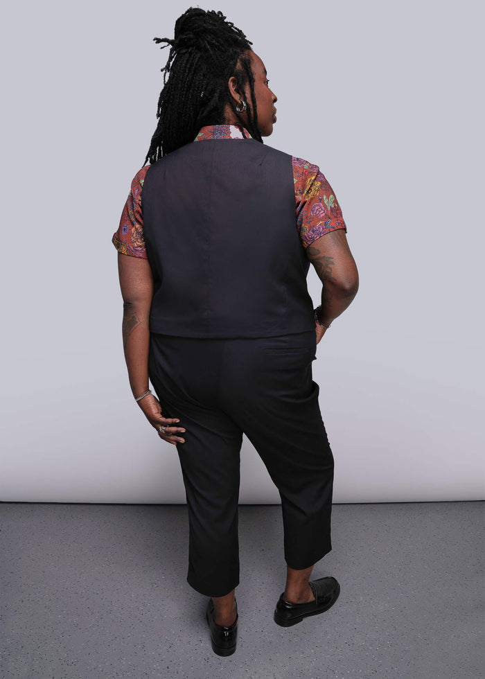 1X=Person wearing a black vest and pants with a patterned shirt against a plain background