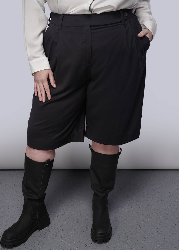 1X=Person wearing black high-waisted shorts and black boots on a plain background