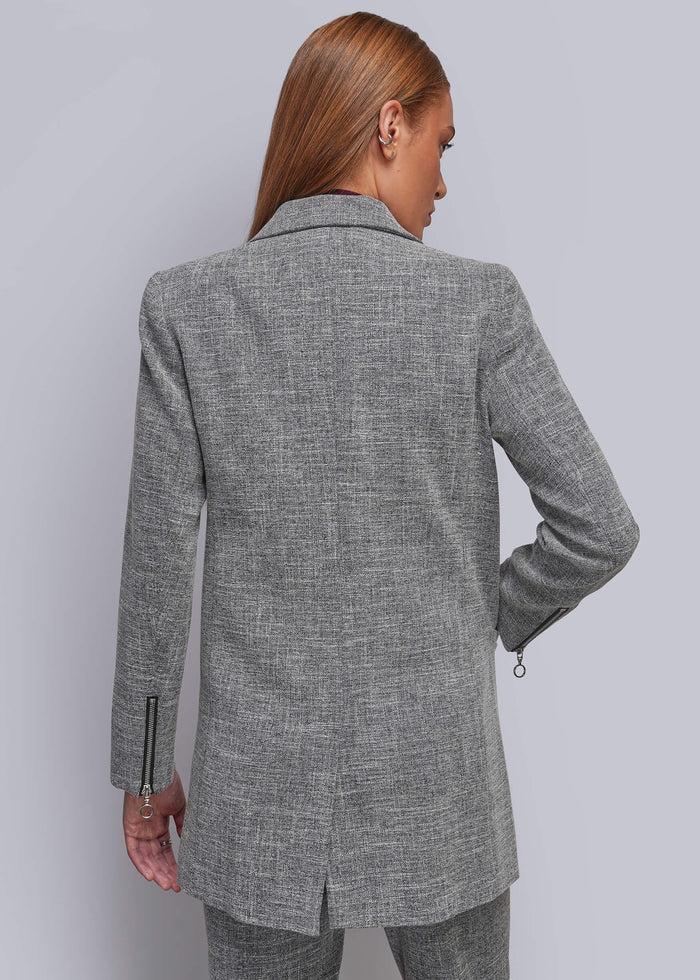 S=A woman shown from the back wearing a gray textured blazer and matching trousers against a light gray studio background.