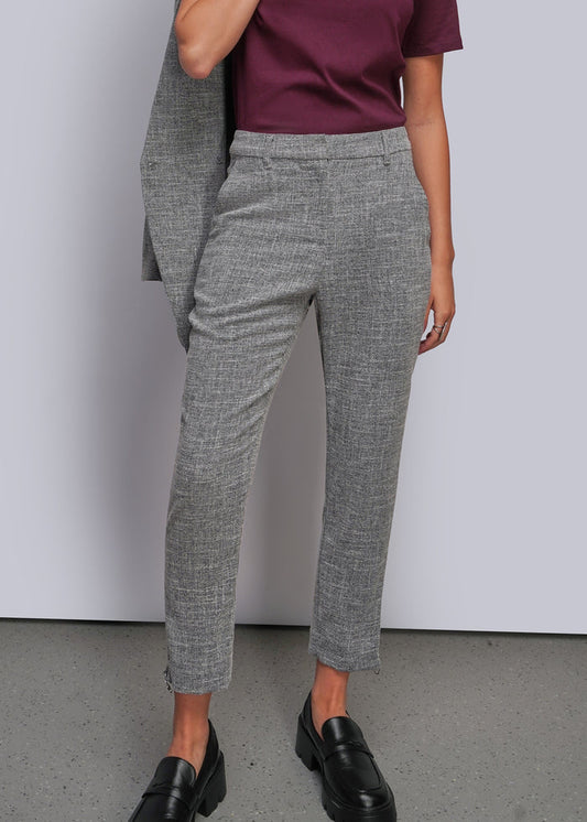 S=A model wearing a pair of gray textured cropped trousers, styled with a dark burgundy t-shirt, a draped gray blazer, and black leather loafers against a light gray studio background.