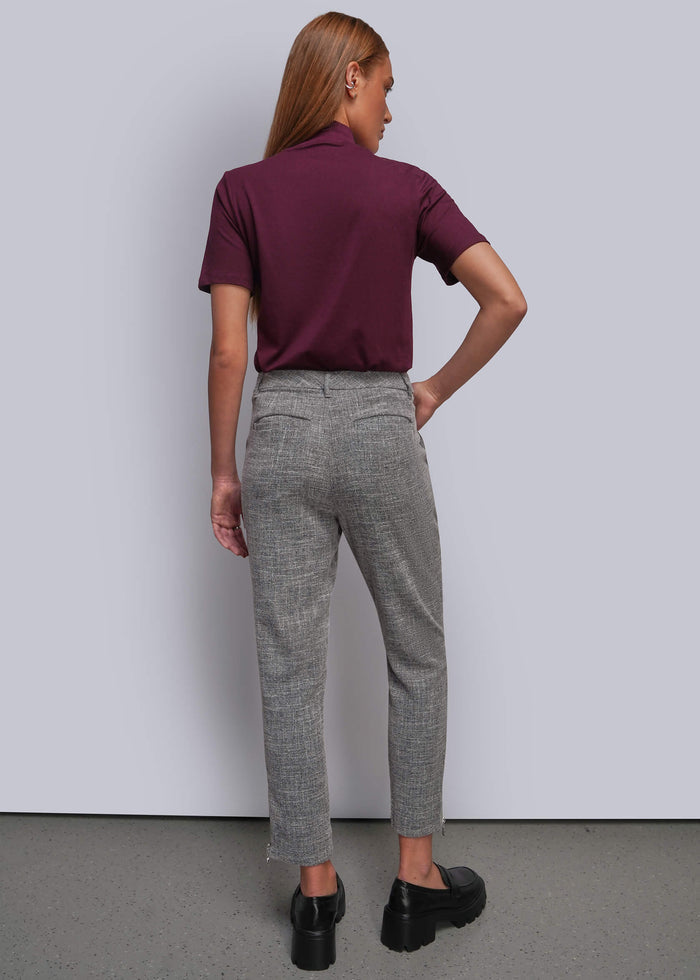 S=A woman is shown from behind wearing a short-sleeve burgundy shirt, gray cropped trousers, and black platform loafers against a light gray studio background.