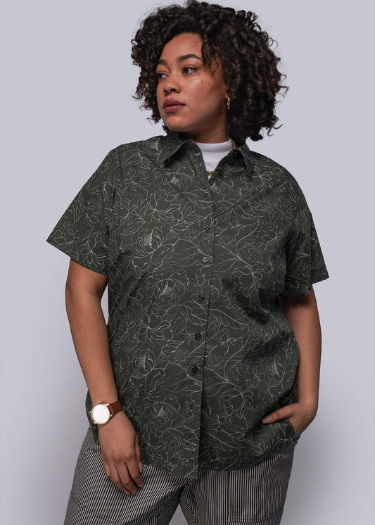 1X=Person wearing a dark green patterned shirt against a plain background