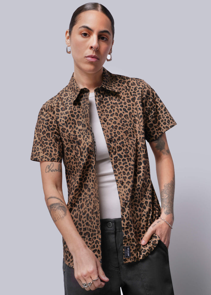 S=Person wearing a leopard print shirt over a white top with a plain background