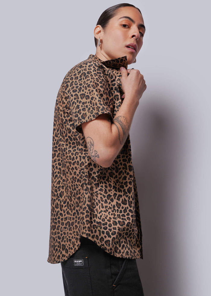 S=Person wearing a leopard print shirt against a plain background
