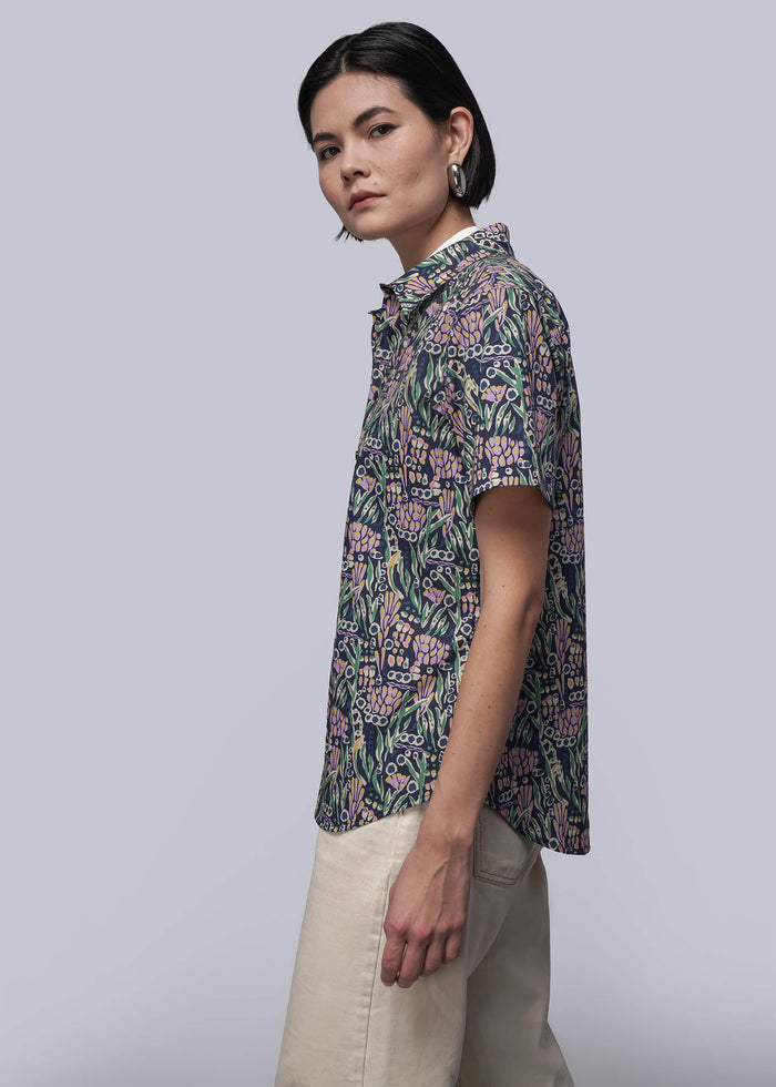 S=Woman wearing a floral patterned shirt against a plain background