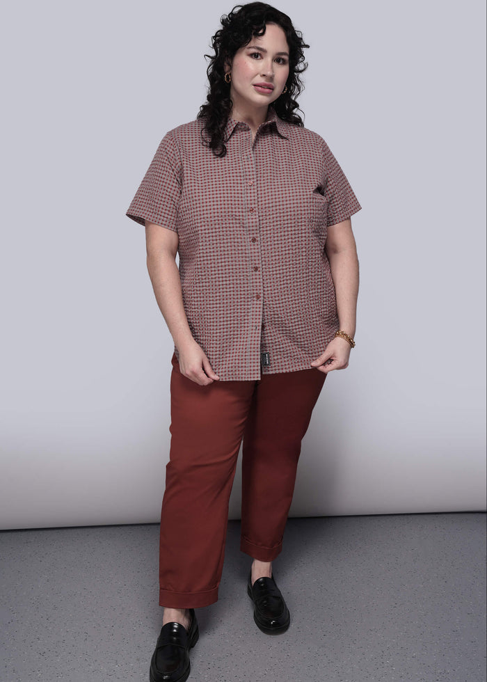 1X=Person wearing a checkered shirt and red pants against a plain background