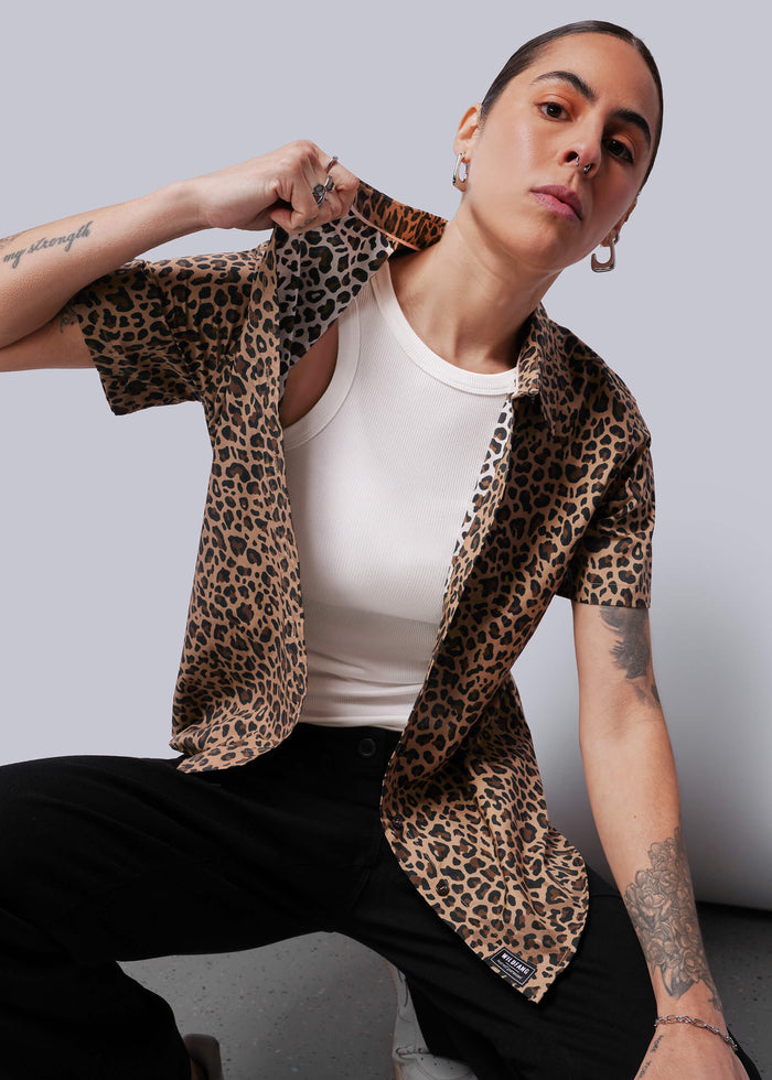 S=Person wearing a leopard print shirt over a white tank top against a plain background