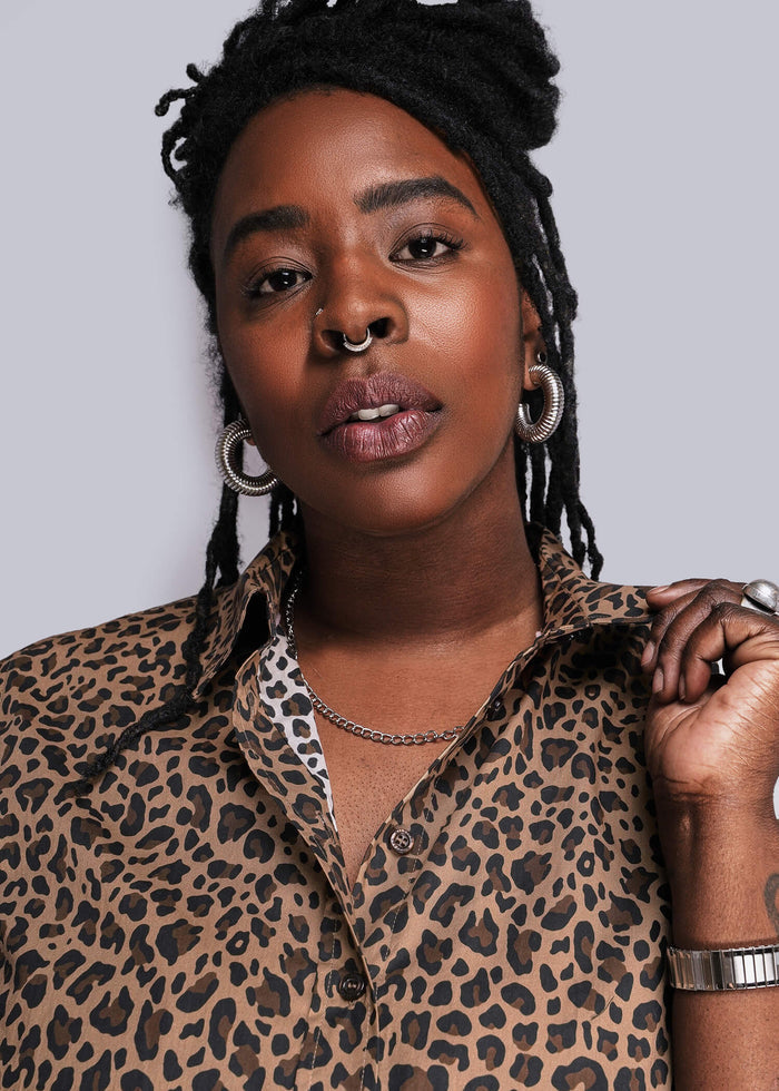 1X=Person wearing a leopard print shirt against a plain background