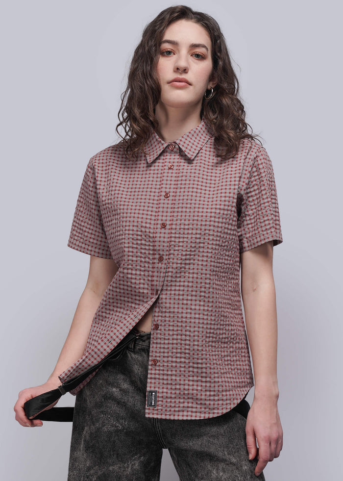 S=Woman wearing a short-sleeve checkered shirt against a plain background