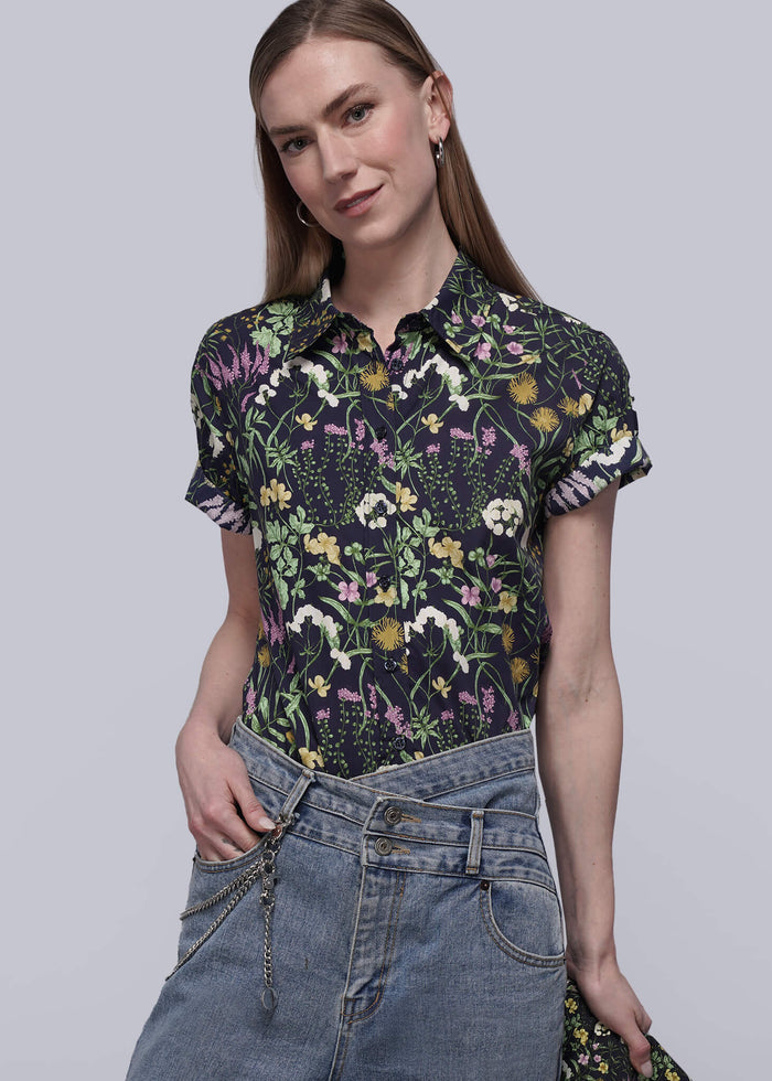 S=Woman wearing a floral shirt and jeans on a plain background